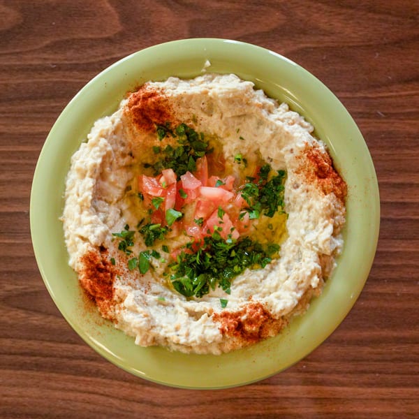 Zest Mediterranean Cuisine's baba ghanoush, garnished with diced tomatoes, parsley, olive oil, and paprika.