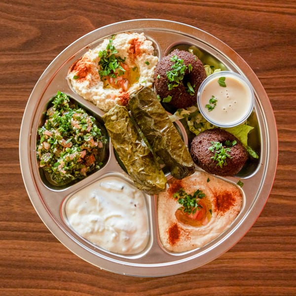 A Zest Mediterranean Cuisine platter with hummus, baba ghanoush, tabbouleh, falafel, and stuffed grape leaves.